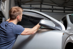 A man putting window tinting film on a car