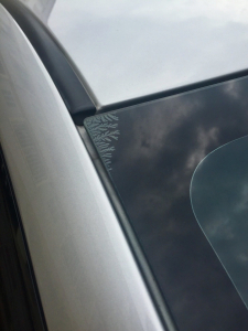 A tinted car windscreen with the corner stripping away