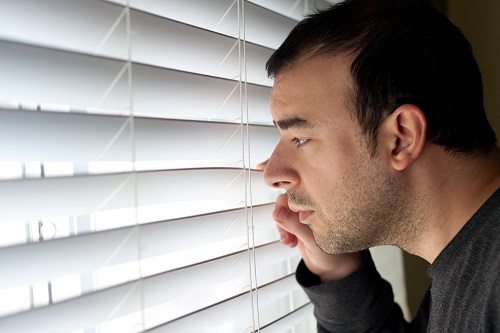 Man peeping outside through the blinds